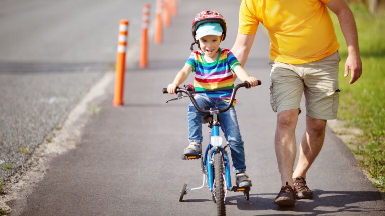 Parent Guiding Young Child Wearing Helmet On Bicycle In Residential Street Representing Child Cycling Accident Claims Uk 2026 Litigation Friend Parental Protection And Legal Rights
