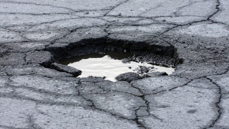 Water-Filled Pothole In Damaged Uk Road Surface Illustrating Pothole Cycling Accident Claim Uk 2026 Highway Defects Causing Injuries Under Highways Act 1980 Section 41 Maintenance Duties