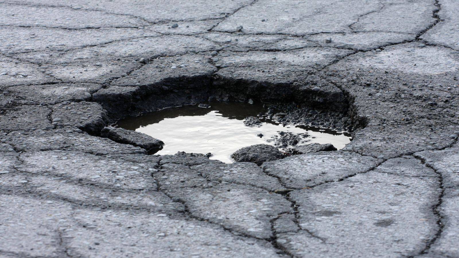 Water-filled pothole in damaged UK road surface illustrating pothole cycling accident claim UK 2026 highway defects causing injuries under Highways Act 1980 Section 41 maintenance duties